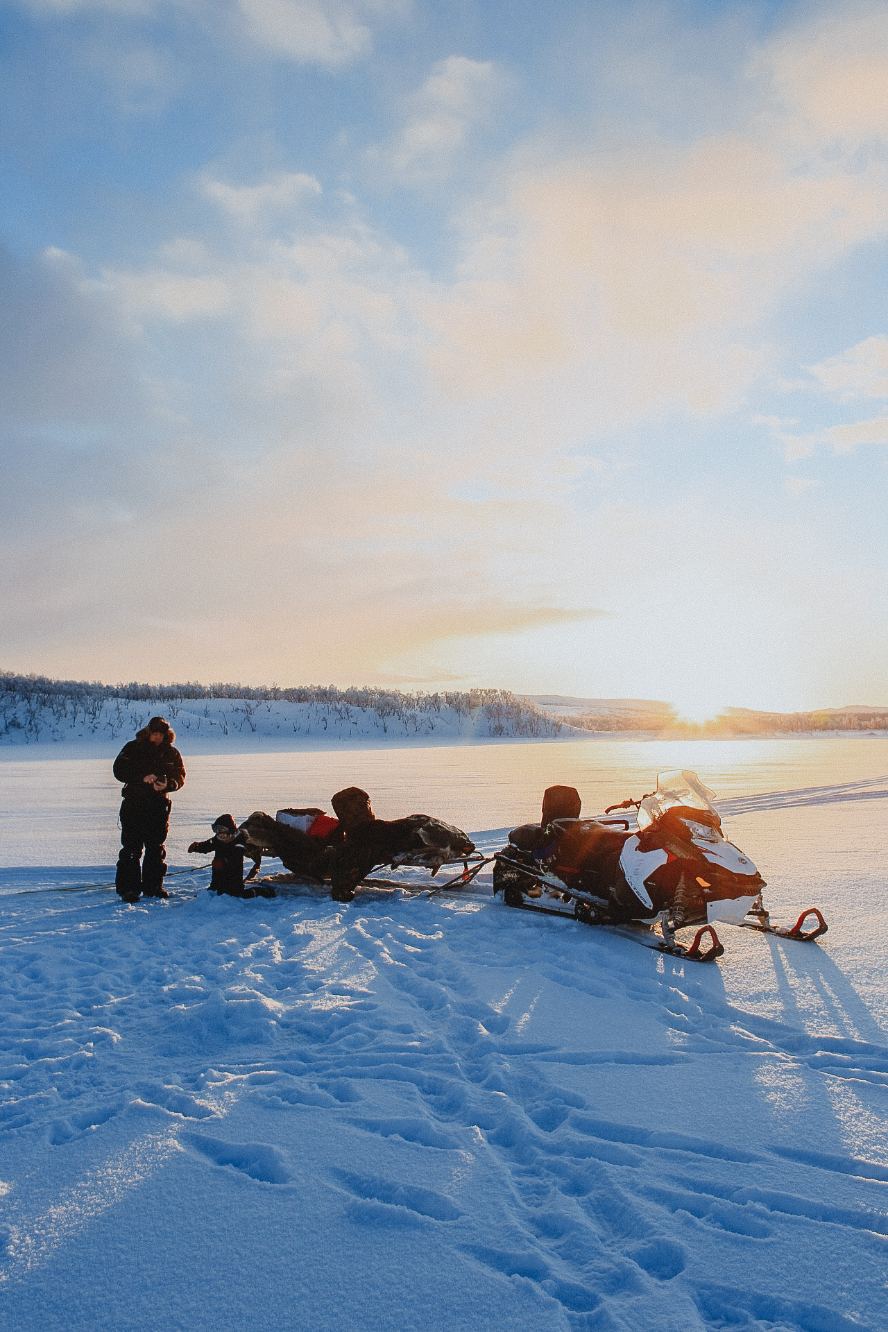 people icefishing next to snowmobiles